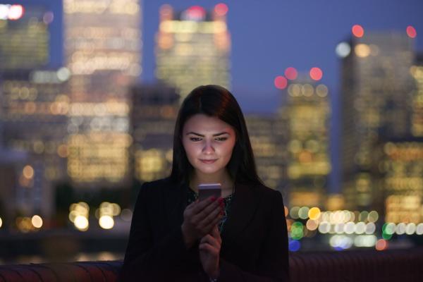 Young woman using smartphone in the city at night